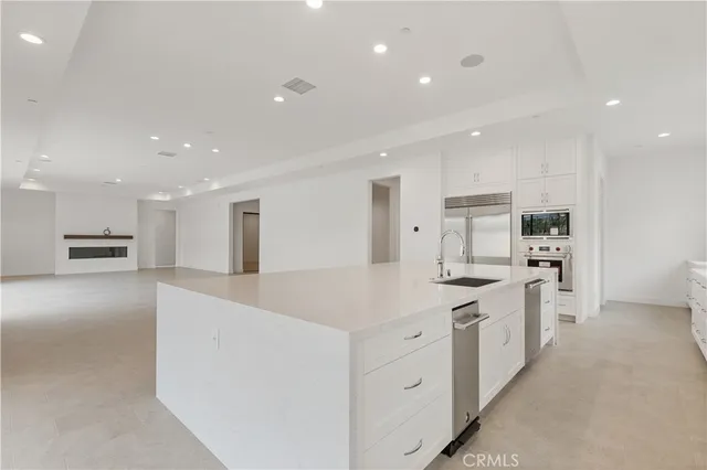 a large kitchen with stainless steel appliances kitchen island a large counter top and a stove top oven with white countertops