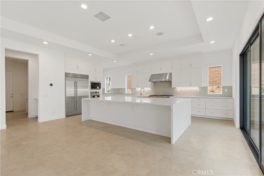 11864 Red Hawk Lane Porter Ranch, CA 91326 - Photo 8 of 15 a large white kitchen with kitchen island a sink stainless steel appliances and cabinets