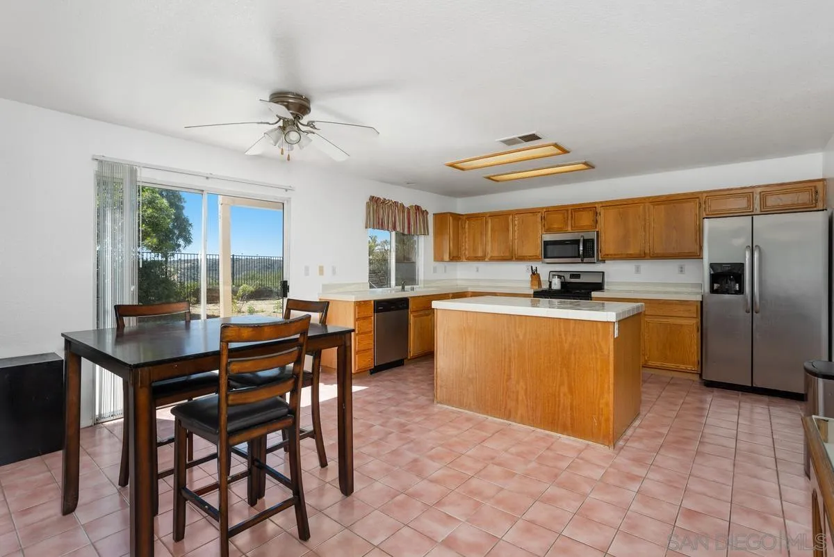 408 Shadow Tree Drive Oceanside, CA 92058 - Photo 5 of 29 a kitchen with stainless steel appliances kitchen island granite countertop a table chairs microwave and cabinets
