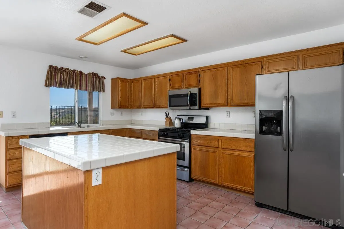 408 Shadow Tree Drive Oceanside, CA 92058 - Photo 9 of 29 a kitchen with stainless steel appliances granite countertop a sink stove refrigerator and a microwave oven
