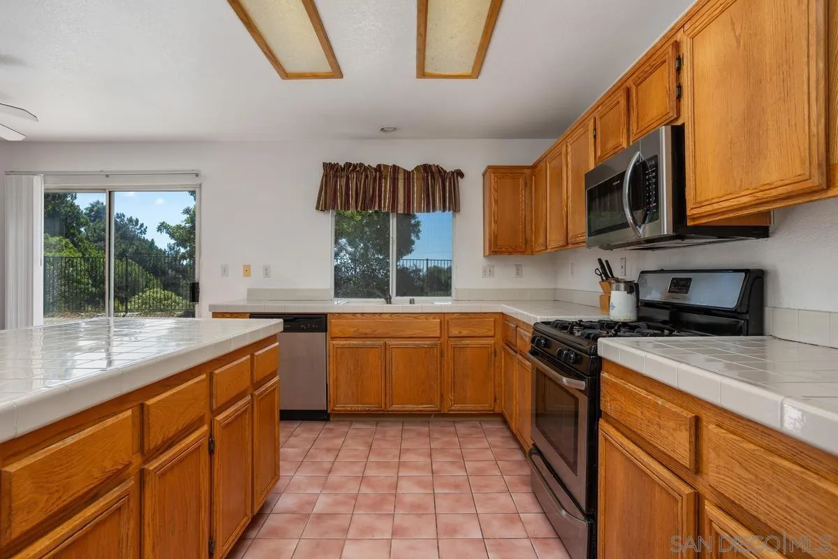 408 Shadow Tree Drive Oceanside, CA 92058 - Photo 10 of 29 a kitchen with stainless steel appliances granite countertop a stove a sink and a microwave