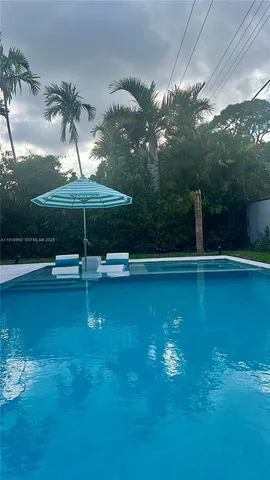 a backyard of a house with plants and large tree