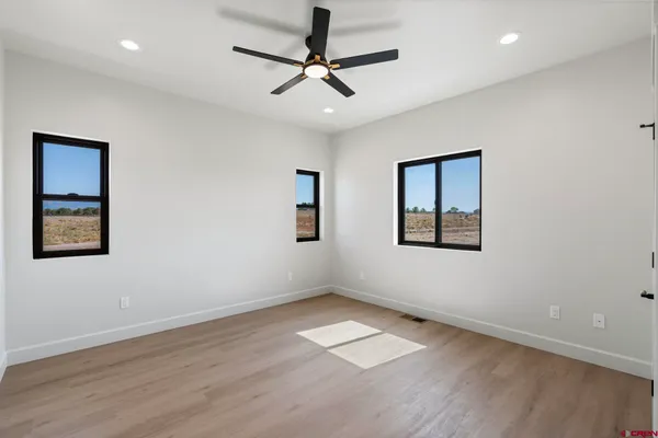a view of empty room with wooden floor and fan