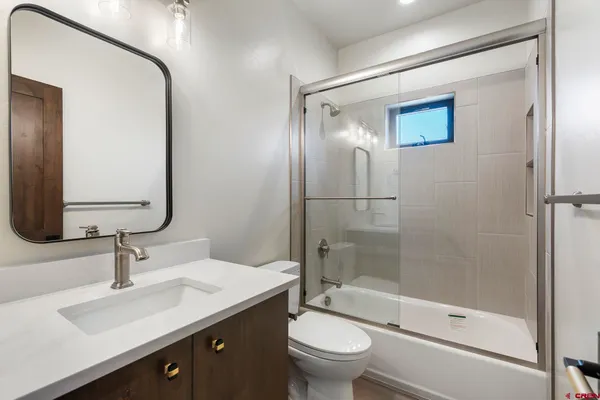 a bathroom with a double vanity sink toilet mirror and shower