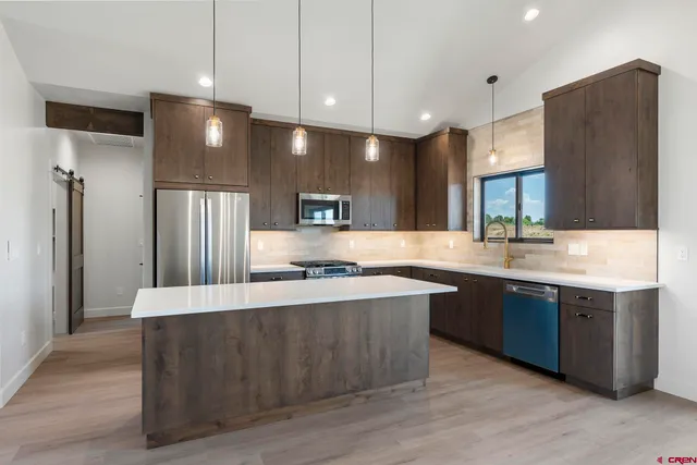 a large kitchen with stainless steel appliances a large counter top space and cabinets
