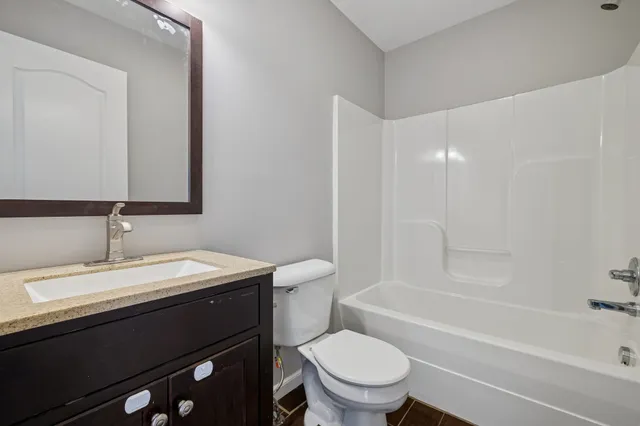 a bathroom with a granite countertop sink toilet a mirror and bathtub