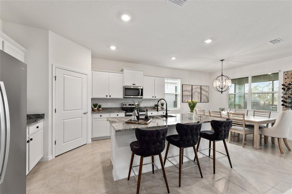4932 Northwest 39th Loop Ocala, FL 34482 - Photo 25 of 64 a kitchen with stainless steel appliances kitchen island granite countertop a table chairs sink and cabinets