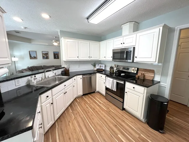 a large kitchen with stainless steel appliances granite countertop a stove a sink and a microwave
