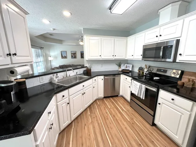 a kitchen with stainless steel appliances granite countertop a sink a stove top oven a counter space and cabinets