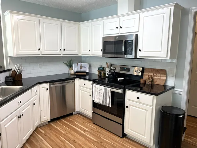 a kitchen with granite countertop white cabinets and black appliances