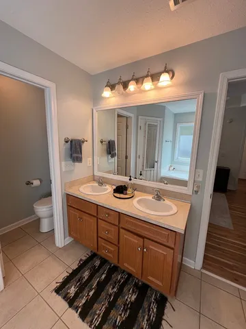a spacious bathroom with a double vanity sink a toilet and a mirror