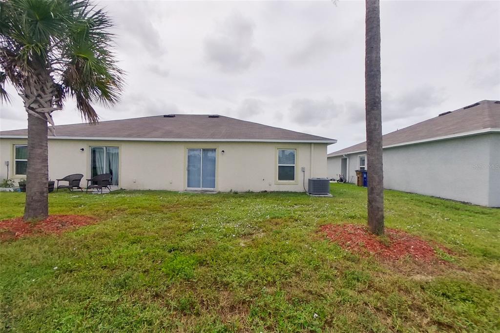 18318 Gibraltar Lane Lehigh Acres, FL 33936 - Photo 14 of 14 a view of a house with a yard and palm trees