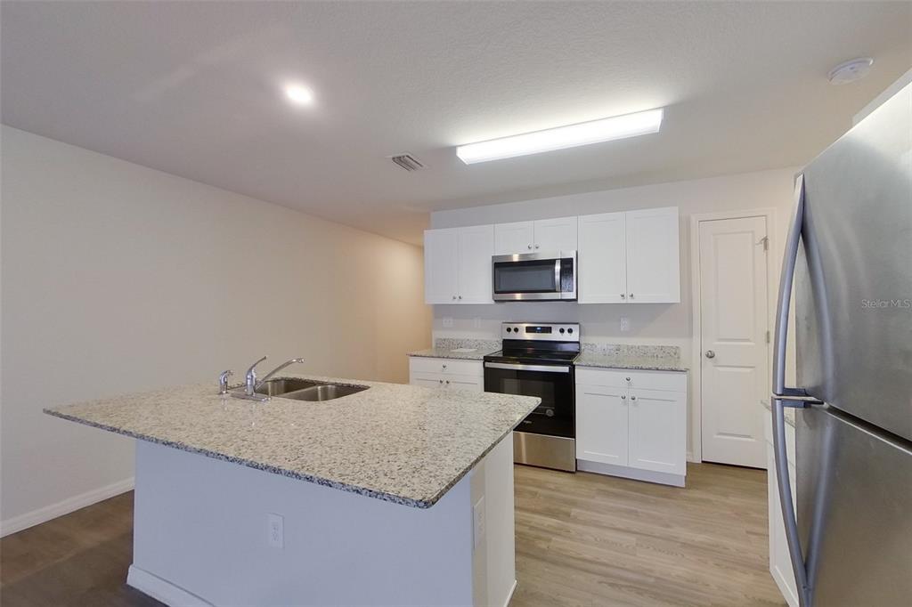 18318 Gibraltar Lane Lehigh Acres, FL 33936 - Photo 3 of 14 a kitchen with stainless steel appliances granite countertop a refrigerator stove microwave and sink