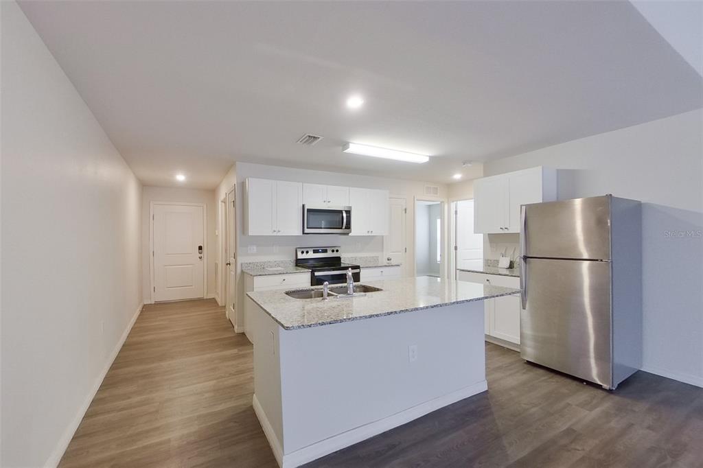 18318 Gibraltar Lane Lehigh Acres, FL 33936 - Photo 4 of 14 a kitchen with stainless steel appliances a refrigerator a stove a microwave and white cabinets