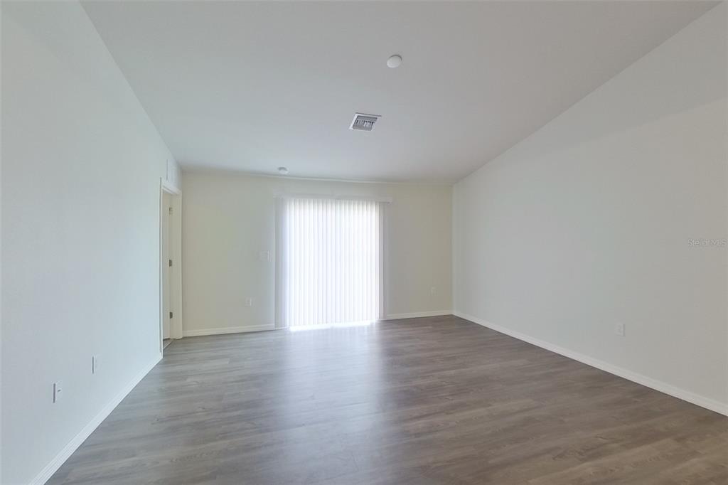 18318 Gibraltar Lane Lehigh Acres, FL 33936 - Photo 7 of 14 a view of an empty room with wooden floor and a window