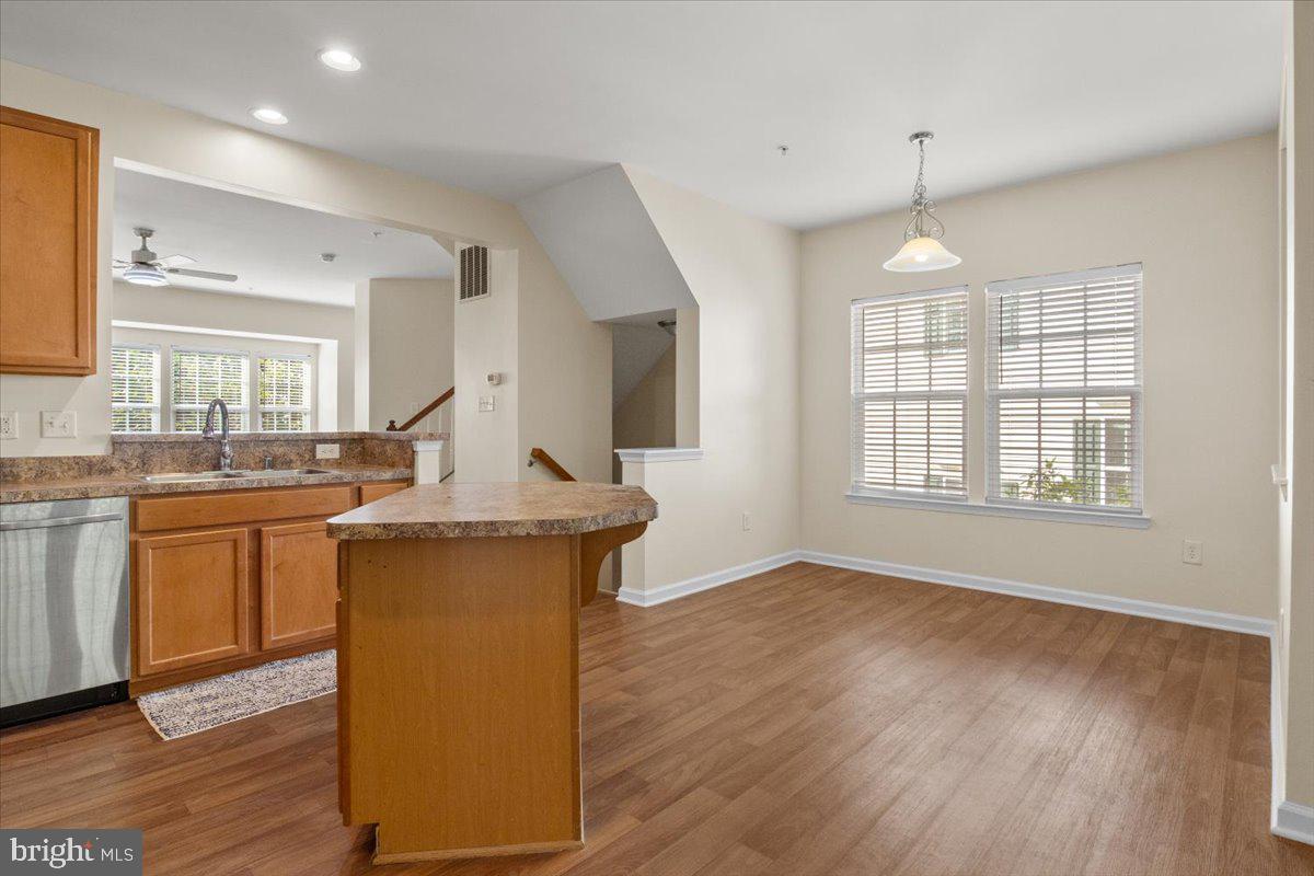 8329 Autumn Crest Lane, Unit 6 Chesapeake Beach, MD 20732 - Photo 11 of 30 a view of a kitchen with kitchen island a sink wooden floor and a counter top space