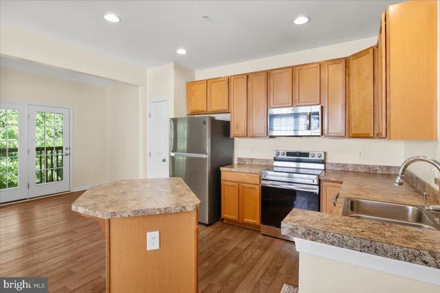 a kitchen with stainless steel appliances granite countertop a refrigerator a sink dishwasher a stove with wooden floors and cabinets