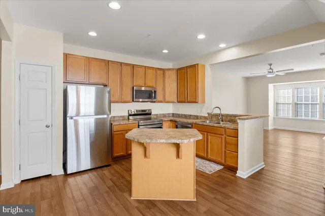 a large kitchen with stainless steel appliances granite countertop a sink a stove a refrigerator a center island and a window