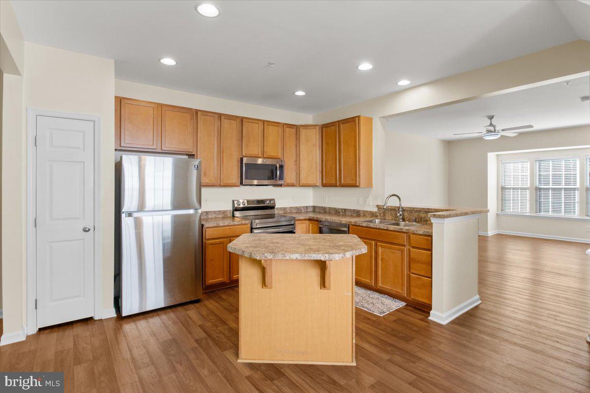 8329 Autumn Crest Lane, Unit 6 Chesapeake Beach, MD 20732 - Photo 9 of 30 a kitchen with stainless steel appliances granite countertop a refrigerator a sink dishwasher a stove with wooden floors and cabinets