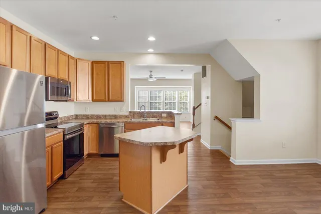 a view of a kitchen with kitchen island a sink wooden floor and a counter top space
