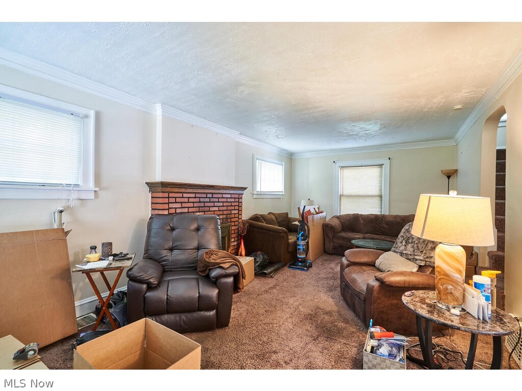 3975 Delmore Road Cleveland Heights, OH 44121 - Photo 5 of 27 Living room featuring a brick fireplace, carpet, crown molding, and a textured ceiling