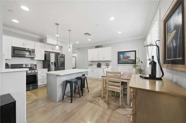 a kitchen with stainless steel appliances granite countertop a refrigerator a stove top oven a sink dishwasher a dining table and chairs with wooden floor