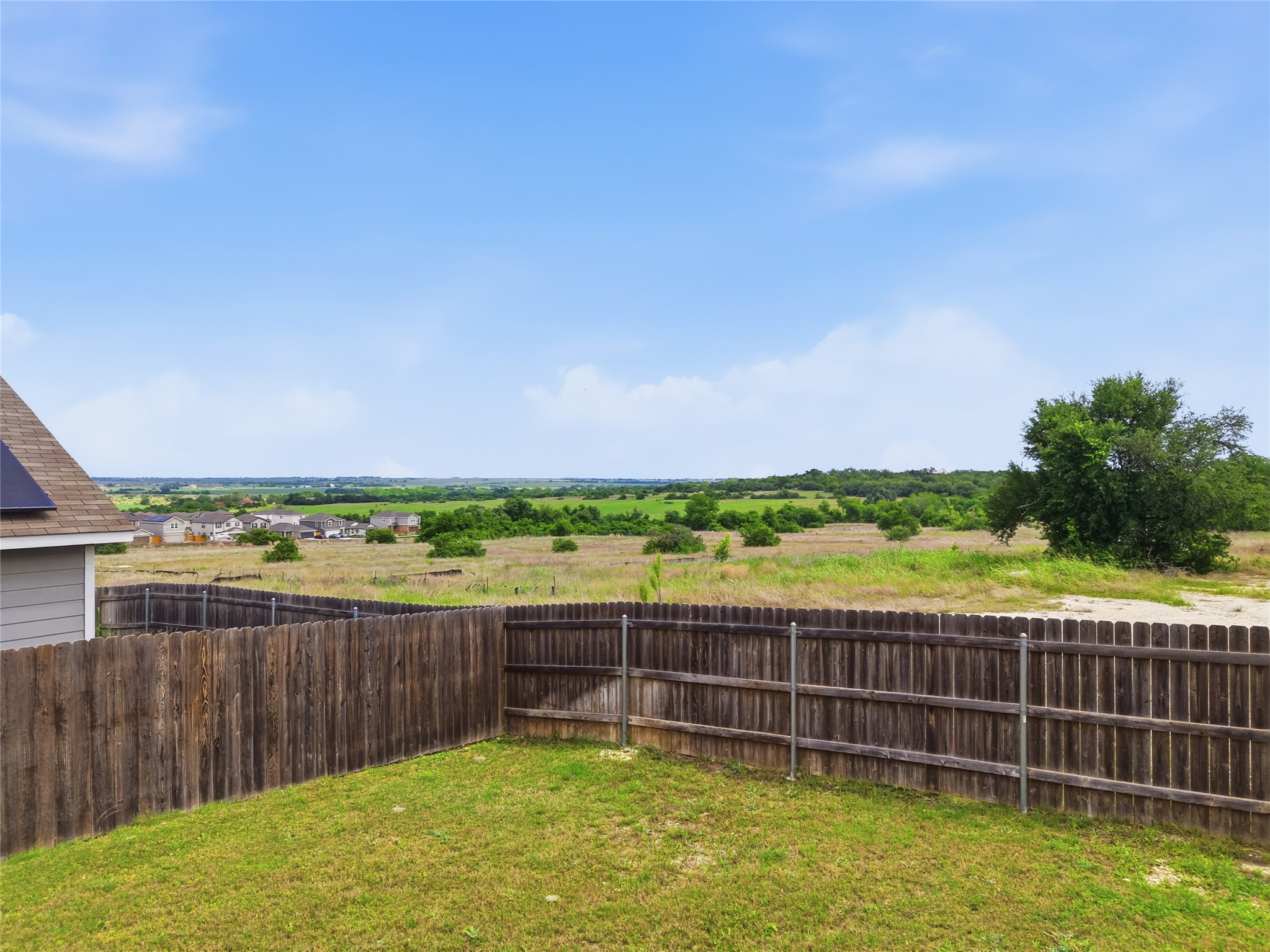 116 Night Riders Way Jarrell, TX 76537 - Photo 35 of 40 Expansive backyard featuring a wood privacy fence, a verdant lawn, and distant natural scenery