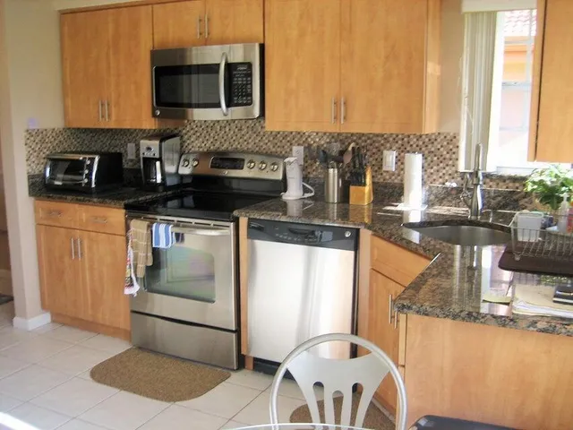 a kitchen with stainless steel appliances granite countertop a stove a sink and a microwave