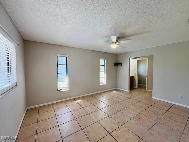 a view of an empty room with window and chandelier fan