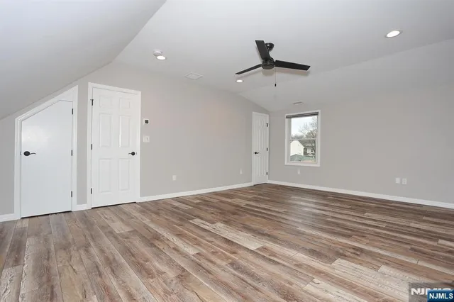 a view of empty room with wooden floor and ceiling fan