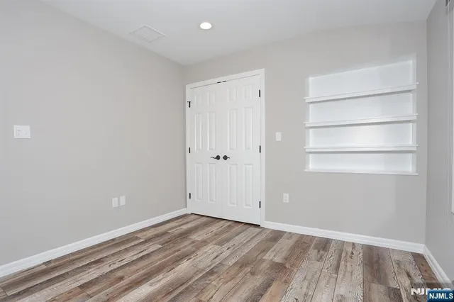 a view of empty room with wooden floor and window