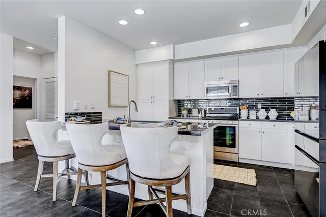 a kitchen with stainless steel appliances a dining table chairs stove and white cabinets