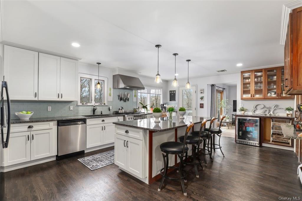 a open kitchen with stainless steel appliances granite countertop a stove and chairs with wooden floors