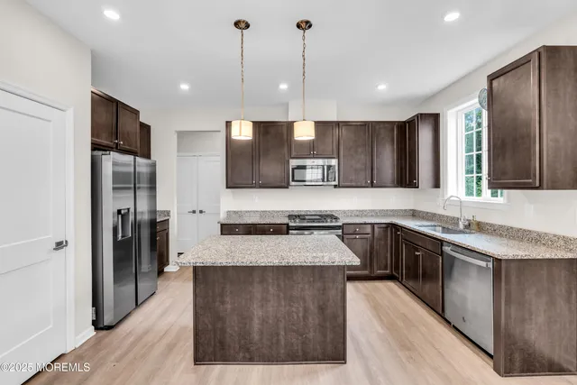 a large kitchen with stainless steel appliances kitchen island granite countertop a stove a sink a refrigerator and a wooden cabinets