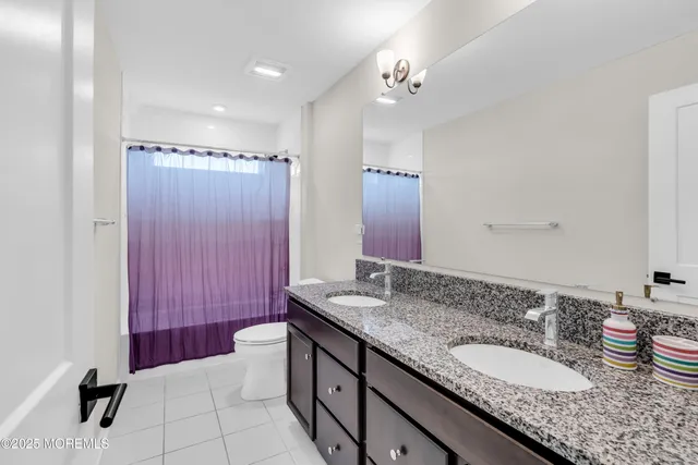 a bathroom with a granite countertop double vanity sink mirror and shower