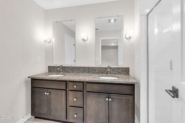 a bathroom with a granite countertop sink a mirror and a shower