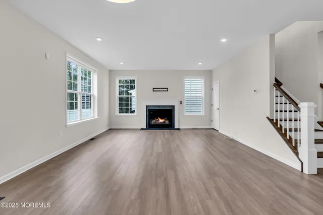 a view of an empty room with wooden floor fireplace and a window