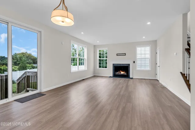 an empty room with wooden floor fireplace and windows