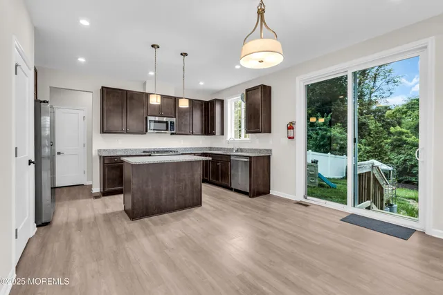 a kitchen with stainless steel appliances granite countertop a stove a refrigerator a sink a microwave oven with a dining table and chairs