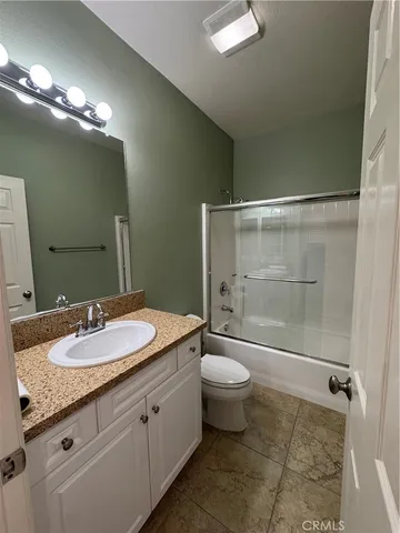 a bathroom with a granite countertop sink a toilet and shower