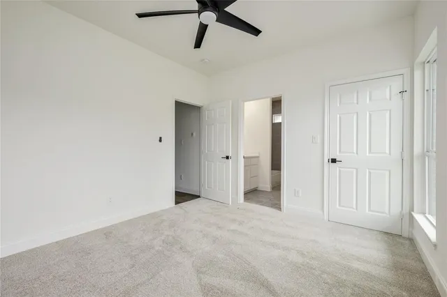 a view of a livingroom with a ceiling fan & windows