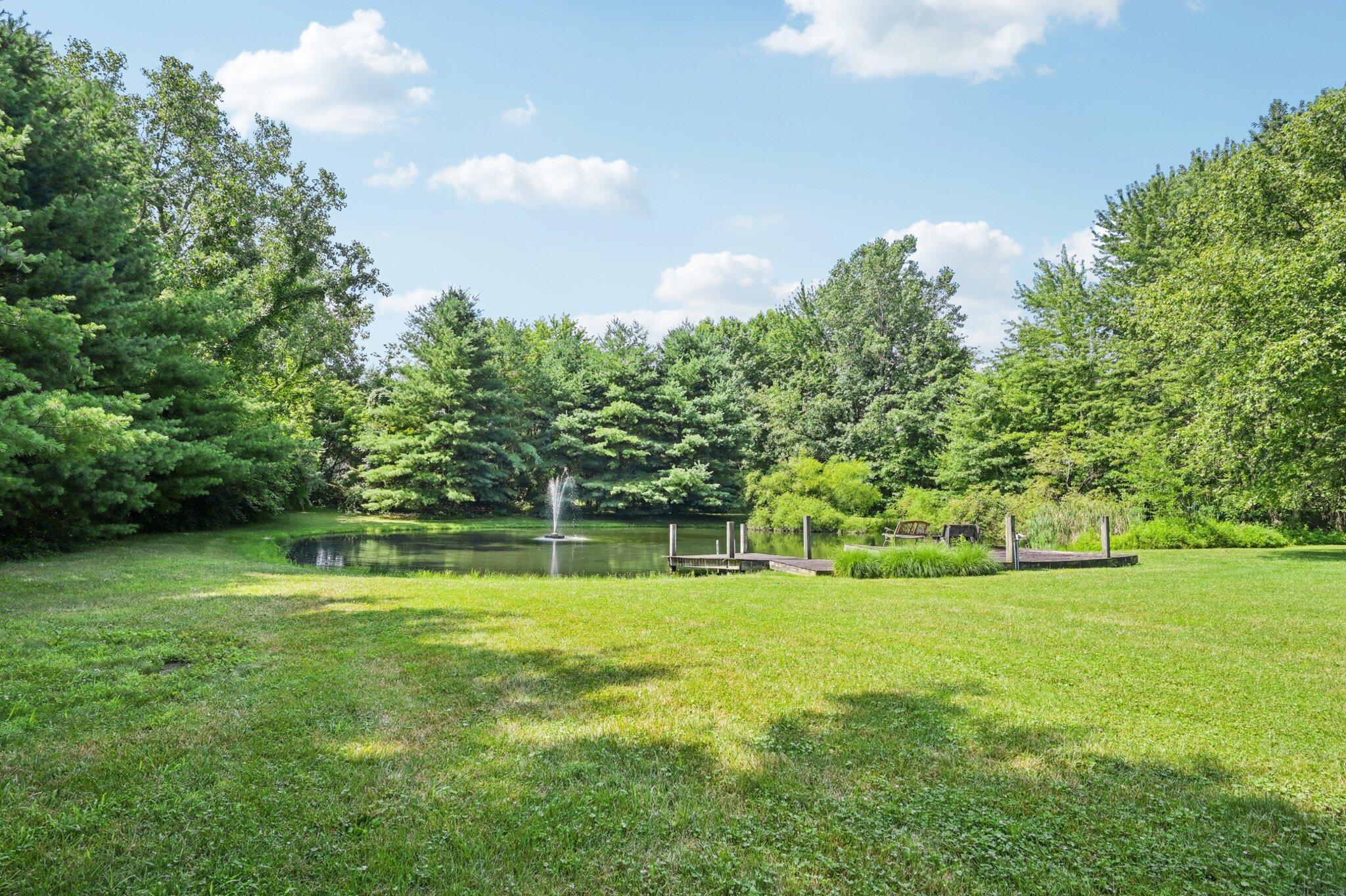 7700 Plumb Road Galena, OH 43021 - Photo 18 of 94 Picturesque pond with dock, seating area, and central fountain—your own backyard oasis for peaceful moments or nature watching.