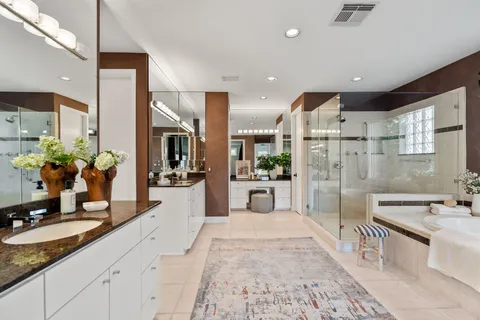 a large white kitchen with stainless steel appliances kitchen island granite countertop a lot of counter space and a sink