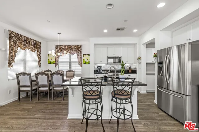 a kitchen with stainless steel appliances a dining table chairs and wooden floor