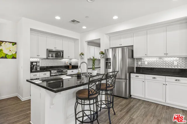 a kitchen with stainless steel appliances granite countertop a refrigerator stove microwave and sink