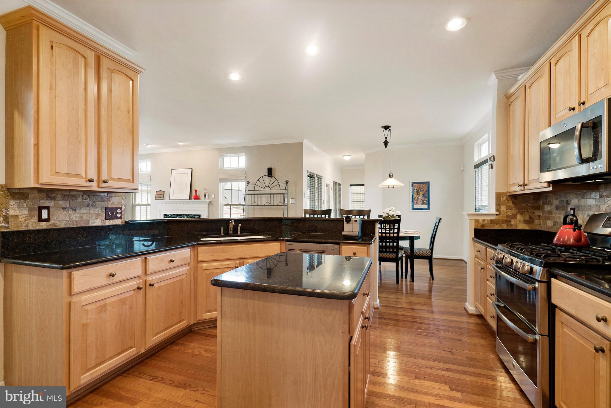 18411 Cornflower Road Boyds, MD 20841 - Photo 9 of 28 a kitchen with stainless steel appliances granite countertop a stove top oven a sink dishwasher a dining table and chairs with wooden floor