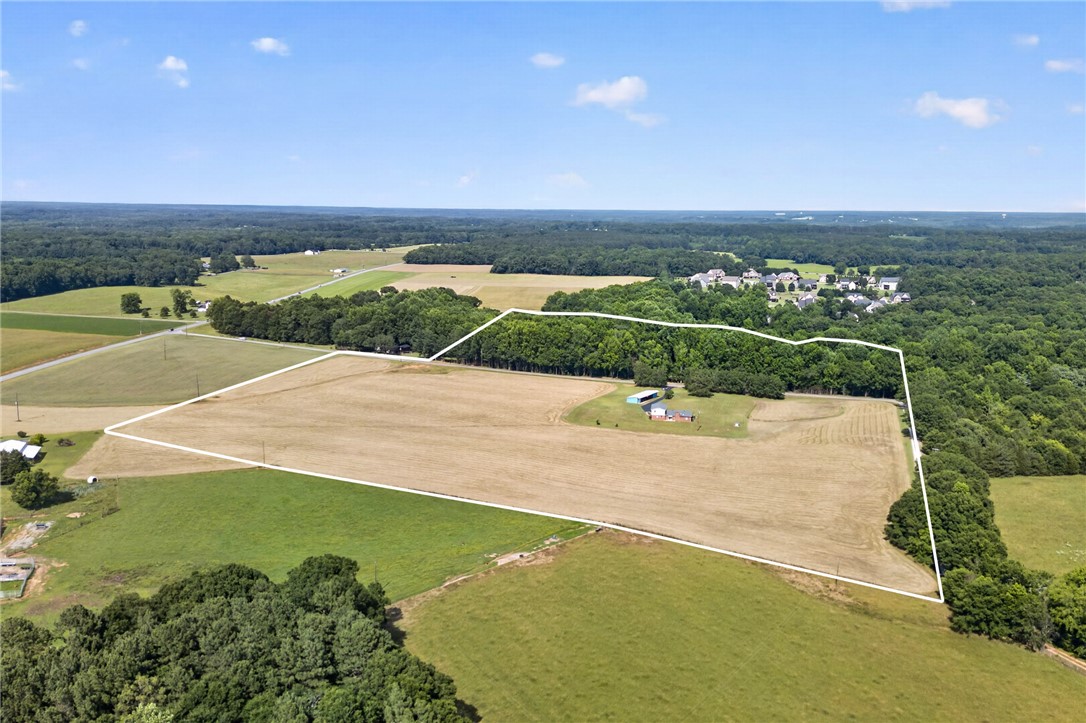 145 State Rd S-4-935 Pendleton, SC 29670 - Photo 33 of 47 An aerial perspective reveals vast, open acreage framed by lush woodlands and neighboring residences.