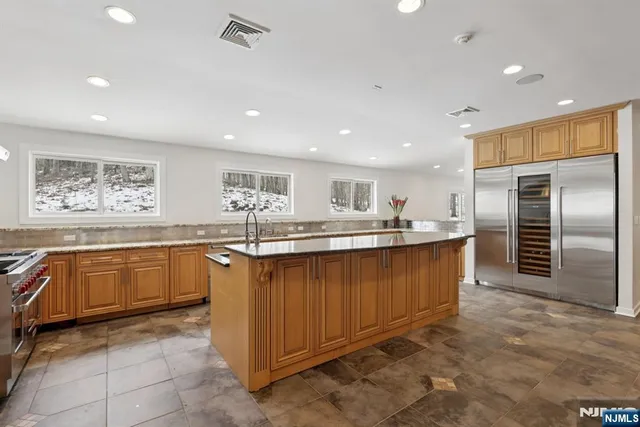 a large kitchen with kitchen island a sink a counter top space and stainless steel appliances