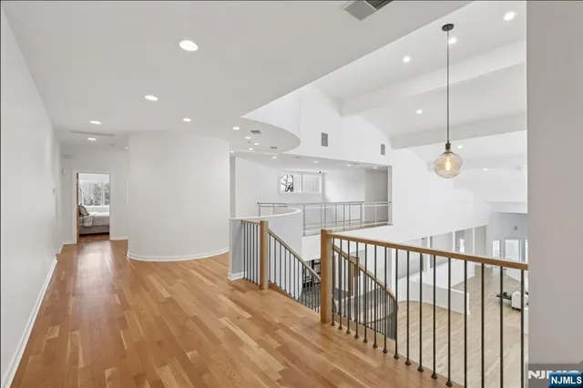 a open kitchen with kitchen island a stove a sink a refrigerator and white cabinets with wooden floor