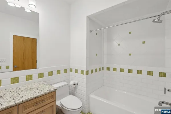 a bathroom with a granite countertop bathtub sink vanity mirror and toilet